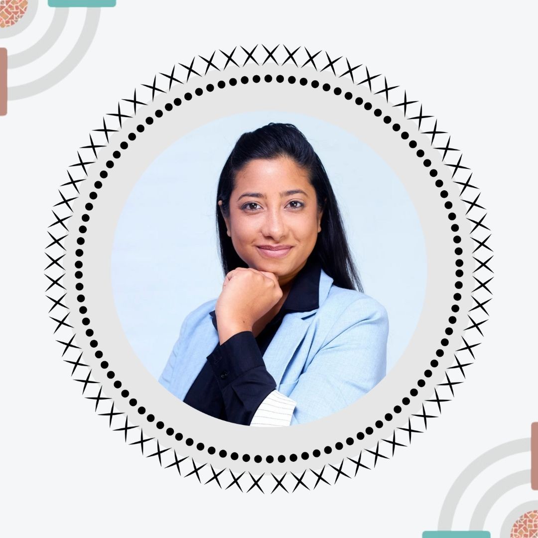 Woman in a light blue blazer smiling, framed by a patterned circular border on a decorative background.